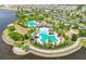 Aerial view showcasing the community pool and amenities surrounded by lush landscaping and a serene lake at 9423 Lemon Drop Loop, Sun City Center, FL 33573