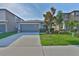 Home exterior with a driveway, two-car garage and landscaped lawn with a tree at 9423 Lemon Drop Loop, Sun City Center, FL 33573