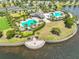 Aerial view of a community pool surrounded by lush landscaping and a lake at 9423 Lemon Drop Loop, Sun City Center, FL 33573