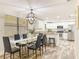Open-concept dining area with a modern glass table, seating for six, and an elegant chandelier, flowing into kitchen at 1025 Reading Rd, Lutz, FL 33558