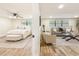 Open floor plan view of living room with neutral furniture and bedroom featuring white bedding and ceiling fan at 1025 Reading Rd, Lutz, FL 33558