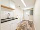 Bright laundry room with modern cabinets, sink, subway tile backsplash, and wood-look floors at 1025 Reading Rd, Lutz, FL 33558