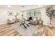 Well-lit living room featuring wood floors, comfortable seating, a modern glass coffee table, and a large window at 1025 Reading Rd, Lutz, FL 33558