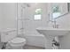 All-white bathroom with a shower-tub combo, pedestal sink, and tiled walls at 1203 E New Orleans Ave, Tampa, FL 33603