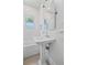 All-white bathroom with a shower-tub combo, pedestal sink, and tiled walls at 1203 E New Orleans Ave, Tampa, FL 33603