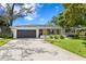 Charming single-story home featuring a well-manicured lawn, gray garage door, and appealing front yard landscaping at 125 Live Oak Ln, Largo, FL 33770