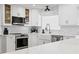 Modern kitchen with white cabinets, quartz countertops, stainless steel appliances, and farmhouse sink at 125 Live Oak Ln, Largo, FL 33770