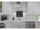 Well-lit kitchen features white cabinets, subway tile backsplash, stainless steel appliances, and a farmhouse sink at 125 Live Oak Ln, Largo, FL 33770