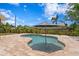 An inviting kidney-shaped pool with a sun umbrella, surrounded by stone pavers and lush landscaping at 125 Live Oak Ln, Largo, FL 33770