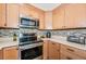 Well-lit kitchen showcases stainless steel appliances, mosaic backsplash, and light wood cabinetry for a modern and clean aesthetic at 12873 Cumberland Dr, Largo, FL 33773