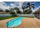Backyard view featuring a kidney-shaped pool with brick surround, lush lawn, and privacy fence at 12873 Cumberland Dr, Largo, FL 33773