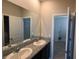 A bathroom features double sinks, granite countertops, and a large mirror, offering a luxurious and functional space at 13111 Pepper Stem St, Spring Hill, FL 34609
