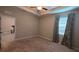 Spacious carpeted bedroom with neutral walls, large window with modern curtains, and a ceiling fan at 13111 Pepper Stem St, Spring Hill, FL 34609