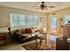 Cozy living room featuring a brown leather couch, ceiling fan, and natural light from large windows at 14530 Apache Ave, Largo, FL 33774