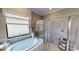 Inviting bathroom features soaking tub beneath window, walk-in shower, and stylish decor at 15021 Oxford Grey Dr, Lakewood Ranch, FL 34211