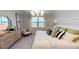 Bright bedroom with large windows, a comfy chair, patterned pillows, and stylish bedside table at 15021 Oxford Grey Dr, Lakewood Ranch, FL 34211