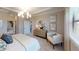 Well-lit bedroom featuring neutral decor, including a wood dresser, white chair, and decorative wall art at 15021 Oxford Grey Dr, Lakewood Ranch, FL 34211