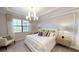 Bright bedroom boasts large windows, coffered ceiling, elegant chandelier, and stylish contemporary decor at 15021 Oxford Grey Dr, Lakewood Ranch, FL 34211