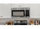 Close up of stainless steel microwave and oven with granite counters and white cabinets at 15107 Oxford Grey Dr, Bradenton, FL 34211