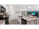 Open kitchen with island seating, granite countertops, white cabinetry, stainless steel appliances, and view to the living space at 15127 Oxford Grey Dr, Bradenton, FL 34211