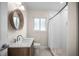 Clean bathroom featuring a modern vanity, round mirror, and glass-enclosed shower at 1794 Santa Barbara Dr, Dunedin, FL 34698
