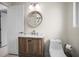 Bathroom featuring a wood vanity, round mirror, and modern toilet at 1794 Santa Barbara Dr, Dunedin, FL 34698