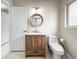 Bright bathroom featuring a wood vanity, round mirror, and modern fixtures at 1794 Santa Barbara Dr, Dunedin, FL 34698