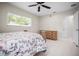 Well-lit bedroom featuring a floral bedspread, ceiling fan, and a wooden dresser with drawers at 1794 Santa Barbara Dr, Dunedin, FL 34698