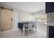 Bright dining room with white chairs, decorative barn door, and views of the landscaped outdoors at 1794 Santa Barbara Dr, Dunedin, FL 34698
