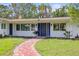 Charming home featuring blue front door, brick path, manicured lawn, and a white exterior at 1794 Santa Barbara Dr, Dunedin, FL 34698