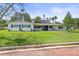 Charming single-story home with manicured lawn, blue shutters, and brick-paved street at 1794 Santa Barbara Dr, Dunedin, FL 34698