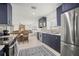Open kitchen with navy blue cabinets, stainless steel appliances, and decorative tile backsplash at 1794 Santa Barbara Dr, Dunedin, FL 34698
