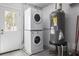 Convenient laundry area featuring a stacked washer and dryer and a tank water heater at 1794 Santa Barbara Dr, Dunedin, FL 34698