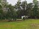 Spacious backyard featuring a hammock, picnic table, and recreational vehicle (RV) surrounded by mature trees at 18452 Fort Dade Ave, Brooksville, FL 34601
