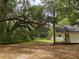 Expansive backyard featuring mature trees providing shade and privacy, with a glimpse of the house at 18452 Fort Dade Ave, Brooksville, FL 34601