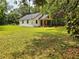Quaint cottage-style home with white siding and a cozy front porch nestled on a spacious lawn at 18452 Fort Dade Ave, Brooksville, FL 34601