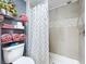Renovated bathroom featuring a tiled shower/bathtub, decorative shower curtain, and shelf storage with towels at 1902 Rebecca Rd, Lutz, FL 33548