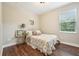 Cozy bedroom featuring a floral-patterned bedspread, wood floors, and a sunlit window at 19191 Pease Pl, Lutz, FL 33558