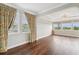 Bedroom with wood floors, two large windows with patterned curtains, and neutral walls at 19191 Pease Pl, Lutz, FL 33558