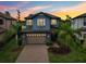 Beautiful two-story home with a brick driveway, blue exterior, lush landscaping, and a two-car garage at 19191 Pease Pl, Lutz, FL 33558