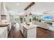 An open kitchen with an island, white cabinets, stainless appliances, and dark wood floors flows to the dining, living areas at 19191 Pease Pl, Lutz, FL 33558