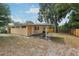 Backyard of home with large trees, grassy area, and a covered patio area at 2044 Temple Ter, Clearwater, FL 33764