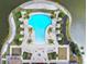 Aerial view of a guitar-shaped community pool area with ample seating, lush landscaping, and lakeside views at 222 Toscavilla Blvd, Nokomis, FL 34275