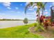 The backyard offers a scenic view of the lake with a grassy lawn and tropical landscaping at 222 Toscavilla Blvd, Nokomis, FL 34275