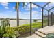Picturesque lakefront backyard with lush landscaping, a screened lanai, and serene water views at 222 Toscavilla Blvd, Nokomis, FL 34275