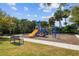 Community playground with slides, swings, and climbing structure, surrounded by lush landscaping and a walking path at 222 Toscavilla Blvd, Nokomis, FL 34275