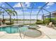 Screened-in pool area with a spa, waterfall feature, and lush landscaping overlooking the lake at 222 Toscavilla Blvd, Nokomis, FL 34275