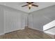 A spacious bedroom with a ceiling fan, wood-look floors, closet, and a door that leads to another room at 23440 Corinne Ave, Port Charlotte, FL 33980