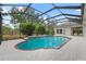 Inviting pool with brick accents set in a screened-in lanai, surrounded by lush greenery at 2901 Laurel Meadow Ct, Plant City, FL 33566