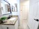 Bathroom featuring granite counters, white cabinets, tiled flooring, and black hardware at 2935 Lichen Ln # D, Clearwater, FL 33760